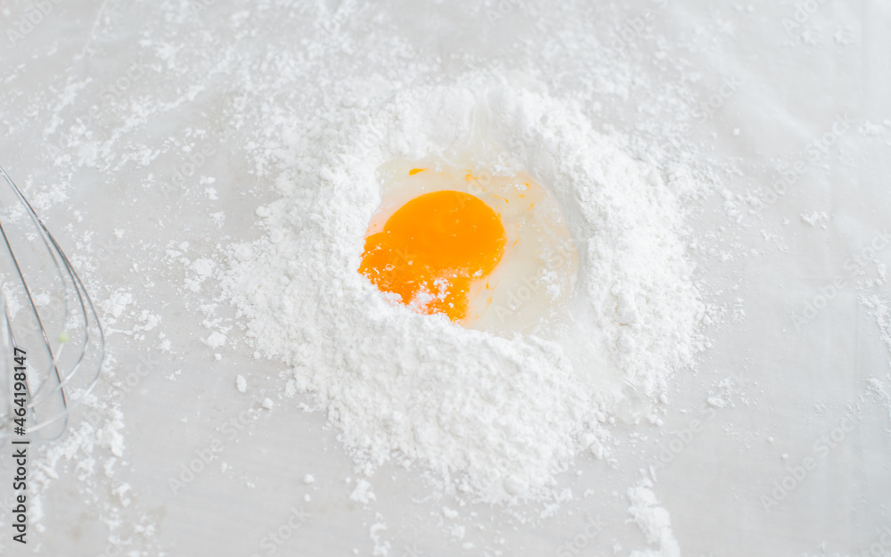 Selective focus on raw egg on table with flour dough for cooking and making bread or croissant for bakery in indoor kitchen at home. Selective focus on raw egg on table with flour dough for cooking and making bread or croissant for bakery in indoor kitchen at home.