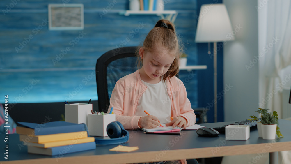 Little child drawing with colorful pencils on notebook at desk for school task and homework. Young girl using supplies to draw on textbook for entertainment and fun after online class. Little child drawing with colorful pencils on notebook at desk for school task and homework. Young girl using supplies to draw on textbook for entertainment and fun after online class.