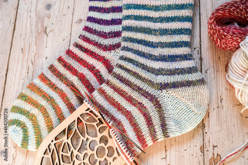 One pair of colourful handknitted socks with ombre rainbow stripes sockyarn laying on vintage wooden floorboards. photo