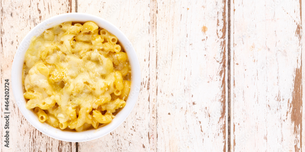 Mac and Cheese, macaroni pasta with cheese in ceramic bowl on white old wood texture background with copy space for text, top view, flat lay, 2 x 1 ratio Mac and Cheese, macaroni pasta with cheese in ceramic bowl on white old wood texture background with copy space for text, top view, flat lay, 2 x 1 ratio