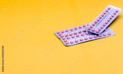 Blister packs of contraceptive pills on yellow background. Hormone pills for treatment hormone acne. Birth control pills. Estrogen and progesterone hormone pills. Pharmacy banner. Prescription drugs. photo