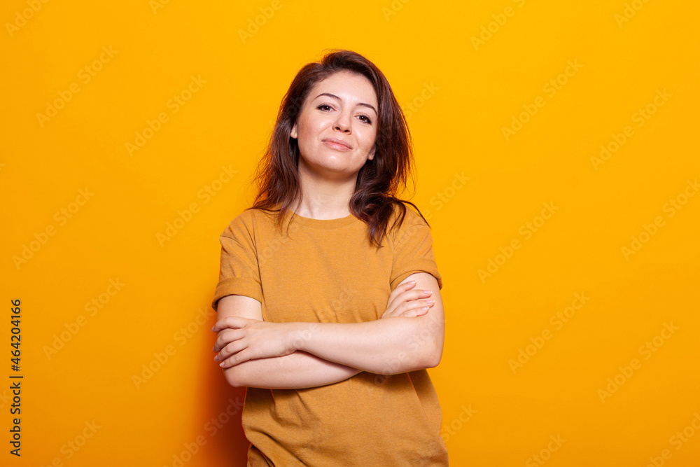 Obraz premium Confident woman standing with crossed arms in front of camera. Portrait of young person posing with casual expression and smiling, standing over isolated background in studio.