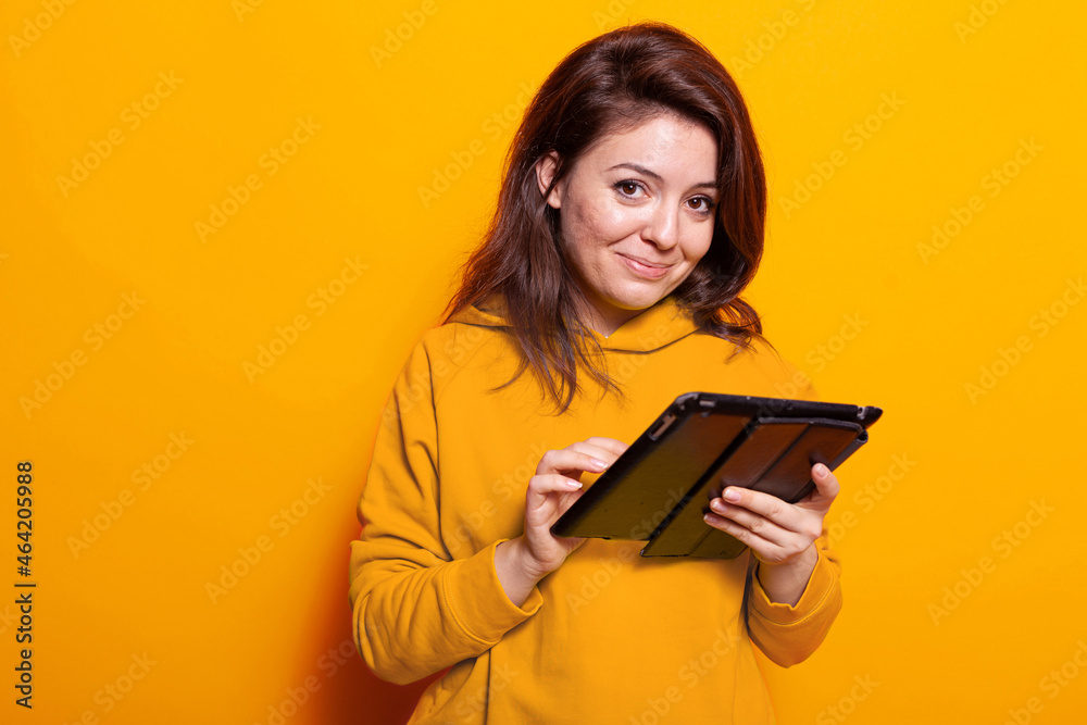 Caucasian adult using digital tablet with touch screen in studio. Cheerful woman holding modern gadget and looking at camera to work on online internet connection. adult with device Caucasian adult using digital tablet with touch screen in studio. Cheerful woman holding modern gadget and looking at camera to work on online internet connection. adult with device