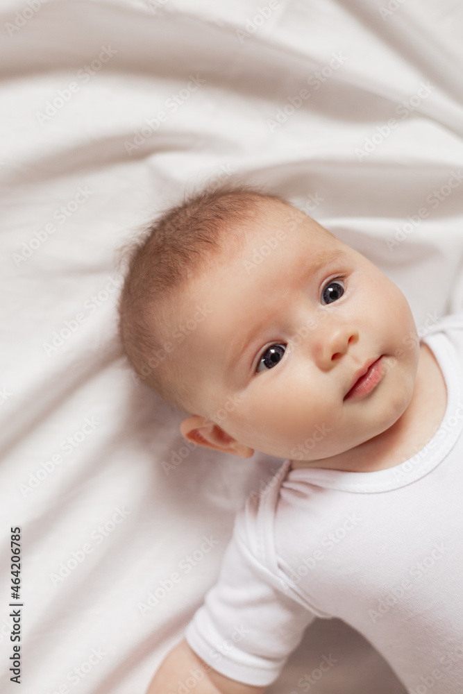 portrait of a cute smiling newborn baby in a white bodysuit on a white background close up. products for children. concept of happy childhood and motherhood. child care. High quality photo portrait of a cute smiling newborn baby in a white bodysuit on a white background close up. products for children. concept of happy childhood and motherhood. child care. High quality photo
