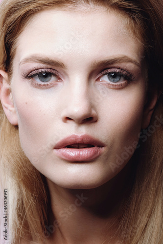 Close-up portrait of beautiful young woman with hairstyle and delicate nude makeup 
