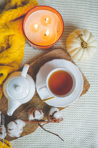 Autumn mood. A cup of hot cappuccino, pumpkins, knitted yellow plaid on a wooden stand. A branch of cotton. copy space.