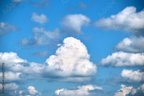 Bright landscape of white puffy cumulus clouds on blue clear sky.