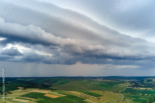 Landscape of dark clouds forming on stormy sky during thunderstorm over rural area.