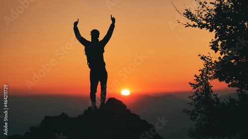 Man in silhouette in front of idyllic sunset in the hills