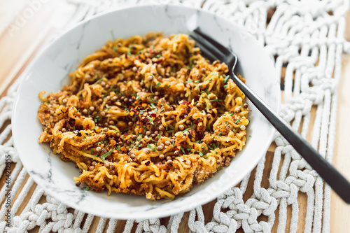 vegan ginger noodles with chilli flakes coriander seeds and tarragon herbs as topping, healthy plant-based food