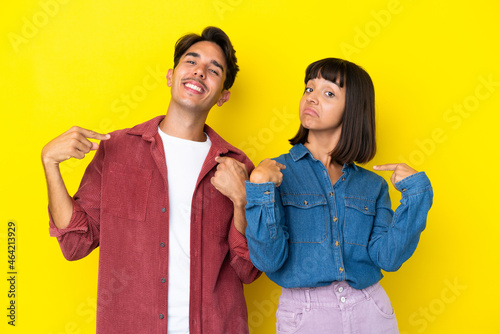 Young mixed race couple isolated on yellow background proud and self-satisfied in love yourself concept
