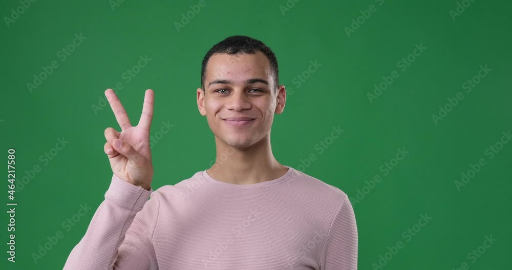 African american man giving v hand sign over green background African american man giving v hand sign over green background