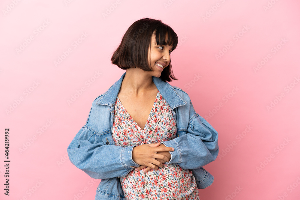 Young pregnant woman over isolated pink background looking to the side and smiling Young pregnant woman over isolated pink background looking to the side and smiling