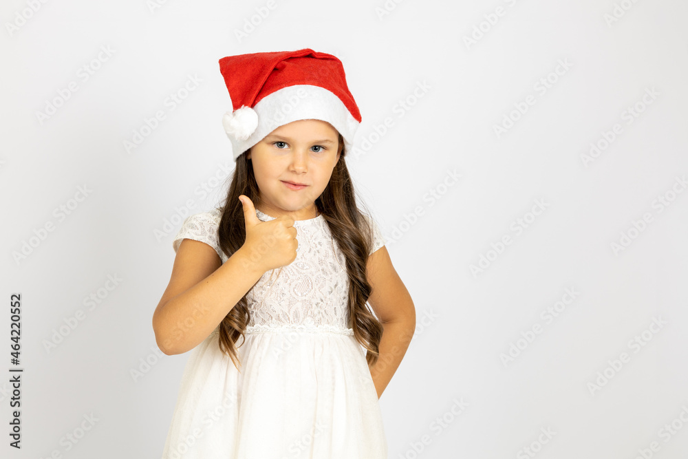 portrait of cute child in red Santa Claus hat gives thumbs up, isolated on white background with copy space. portrait of cute child in red Santa Claus hat gives thumbs up, isolated on white background with copy space.