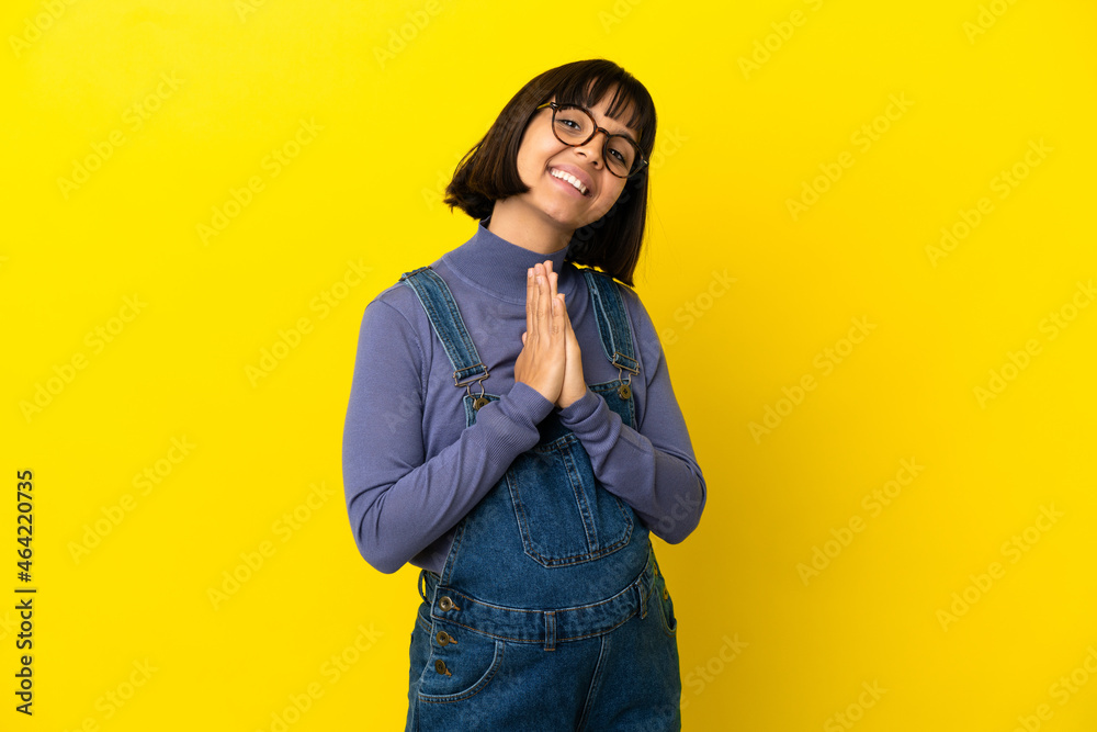 Fototapeta premium Young pregnant woman over isolated yellow background keeps palm together. Person asks for something