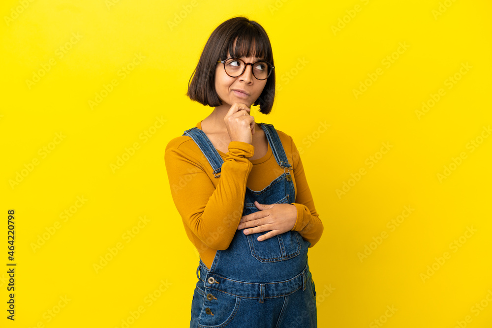 Young pregnant woman over isolated yellow background having doubts and thinking Young pregnant woman over isolated yellow background having doubts and thinking