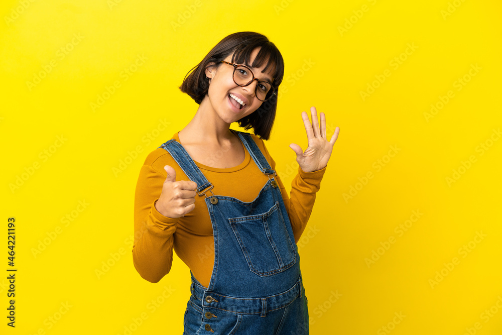 Young pregnant woman over isolated yellow background counting six with fingers Young pregnant woman over isolated yellow background counting six with fingers