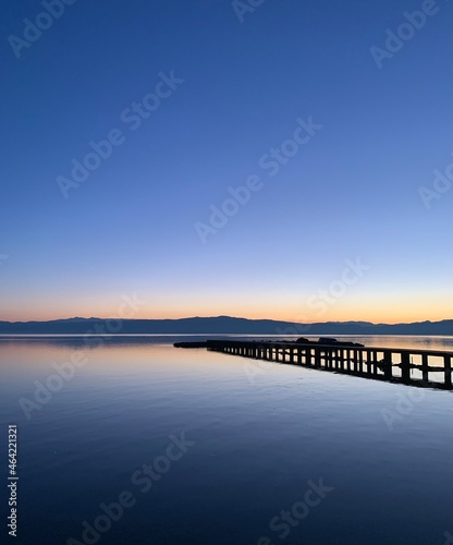 Silhouette of a long pier at the surface of the lake, sunset time, natural colors