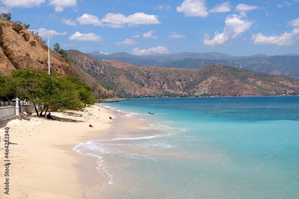 The stunning coastal landscape of turquoise ocean, sandy beach and hills in Dili, Timor Leste