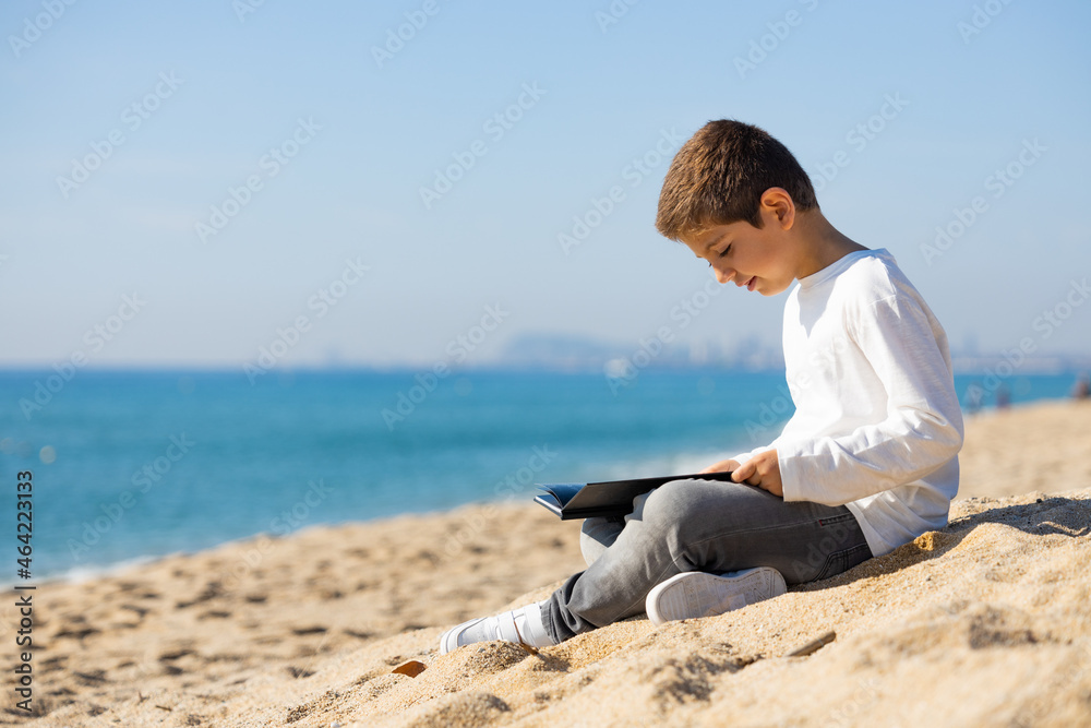 Little kid reading a book on the beach Little kid reading a book on the beach