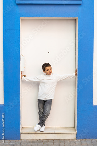 Little kid in front of a blue and white door