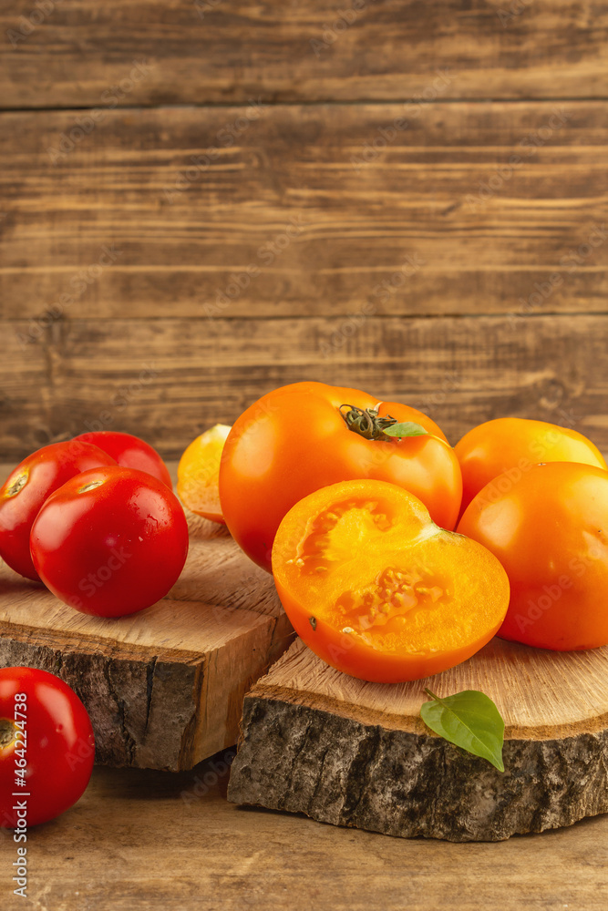 Assorted ripe tomatoes on a wooden stand. Fresh red and orange organic vegetables