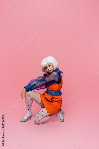 Asian pop art woman in white wig looking at camera on pink background