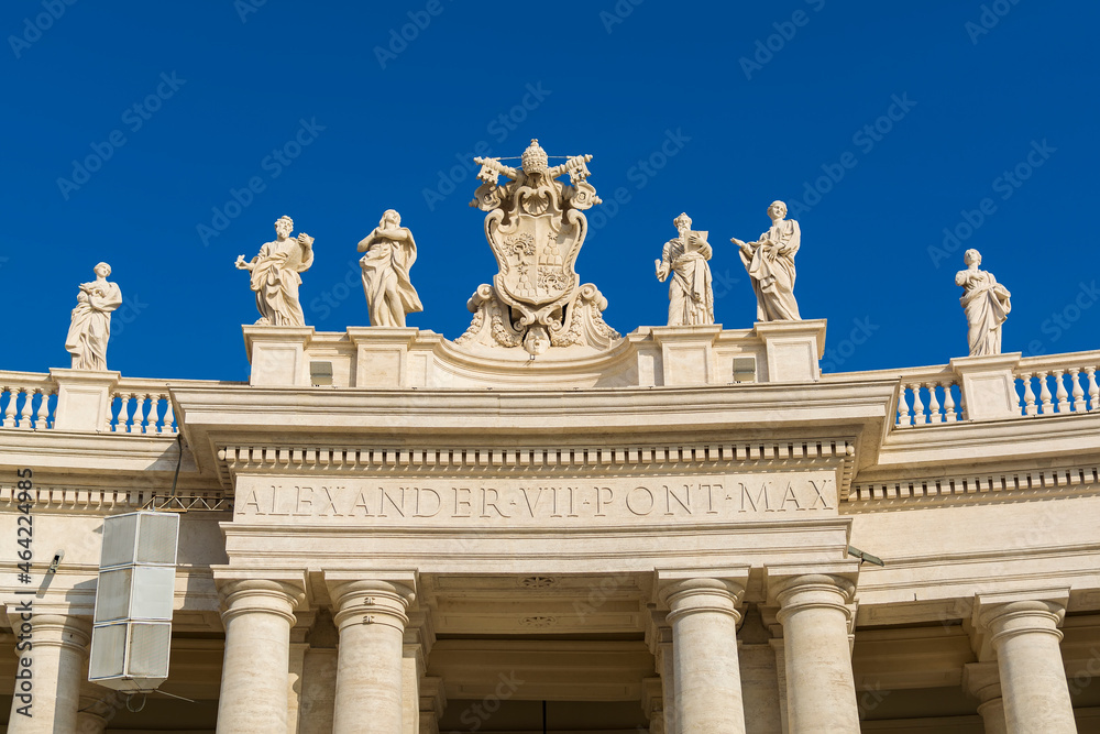 A view of Vatican city coat of arms and saints statues on top of colonnades in Piazza San Pietro (St. Peter's Square)