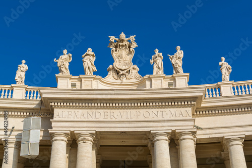A view of Vatican city coat of arms and saints statues on top of colonnades in Piazza San Pietro (St. Peter's Square)