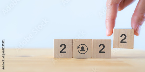 Re-skill concept in 2022. Training employees on an entirely new set of skills for business growth and digital transformation. Man holds wood cube "2022" with re-skill icon. HRM background. Copy space.