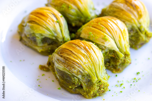 A close-up shot of Turkish dessert baklava slices on a white plate. Selective focus on foreground.