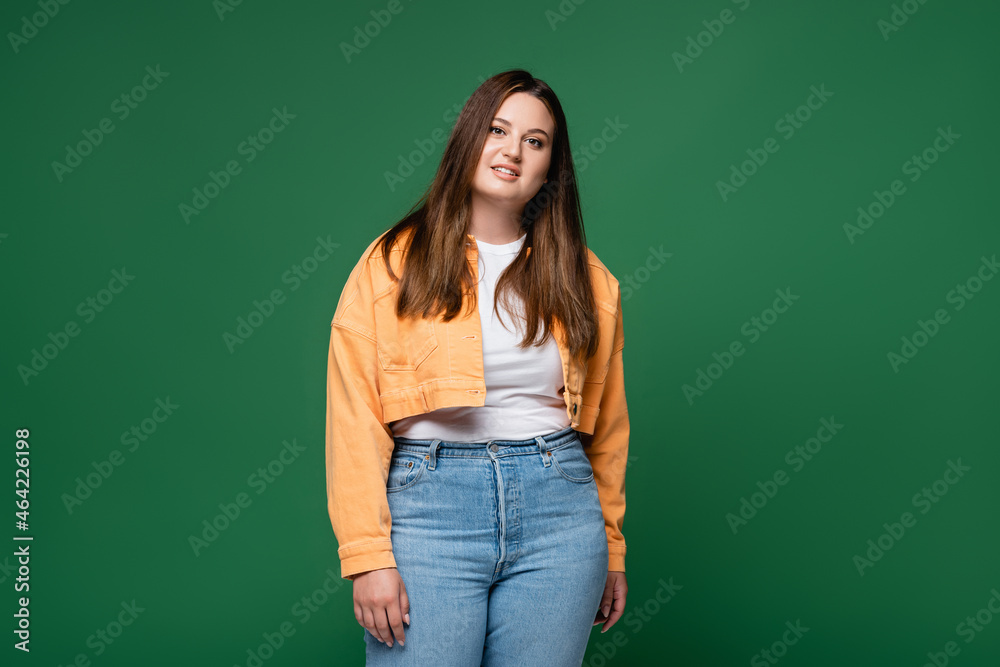 Brunette plus size woman in casual clothes smiling at camera isolated on green Brunette plus size woman in casual clothes smiling at camera isolated on green