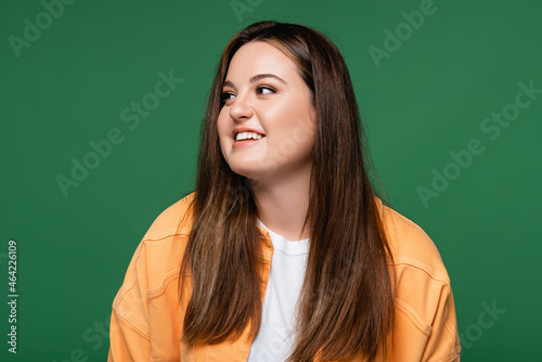 Positive woman with overweight looking away isolated on green