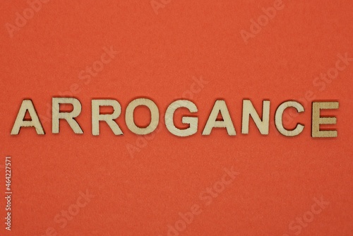 text the word arrogance from gray wooden small letters on an red table