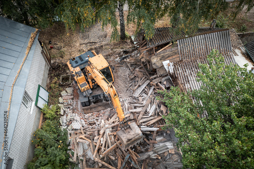 Demolition of building aerial view. Excavator breaks old house. Freeing up space for construction of new building.