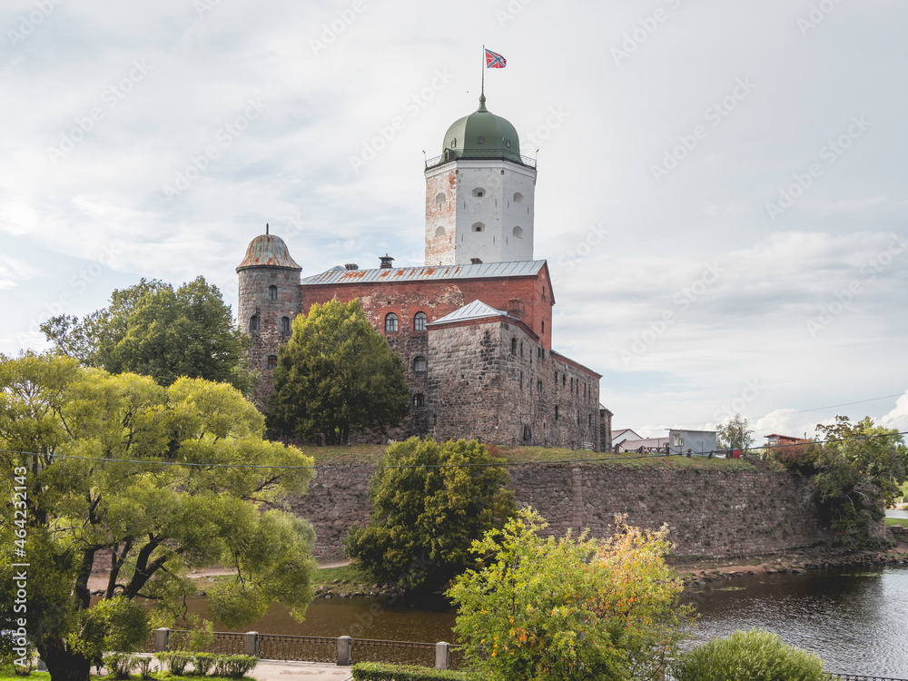 Medieval Vyborg Castle is Swedish-built fortress. White tower of Saint Olav with flag. Historical and architectural landmark.