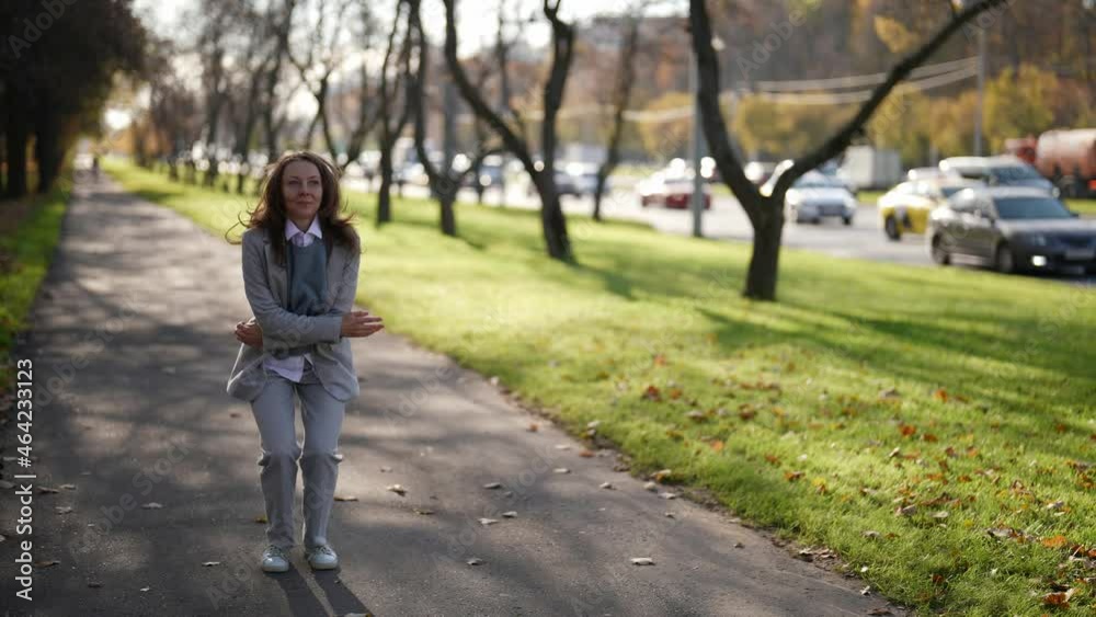 An attractive adult woman is dancing while walking along a city street. Jumping with happiness in a suit. The concept of emotions. An attractive adult woman is dancing while walking along a city street. Jumping with happiness in a suit. The concept of emotions.