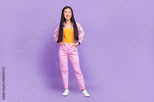 Full size photo of sweet millennial brunette lady look wear pink jacket jeans sneakers isolated on violet background