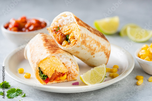 Foto Breakfast vegetarian burrito wrap with omelette and vegetables on a plate