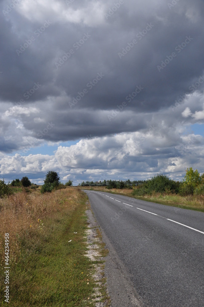 Panorama along a deserted road. View of the road before the rain. Clouds in the sky.