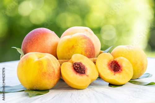 Yellow Peach with sliced on the wooden table over blurred greenery background, Fresh peach on wooden plate in wooden Background.