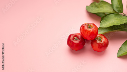 Pile of ripe red acerola cherries isolated on a pink background. High vitamin C and antioxidant fruits. Side view. Space for text. Close-up photo. Concept of healthy fruits photo