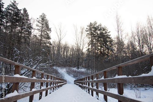 Winter snow-covered wooden bridge to the park. Perspective photo and copy space.