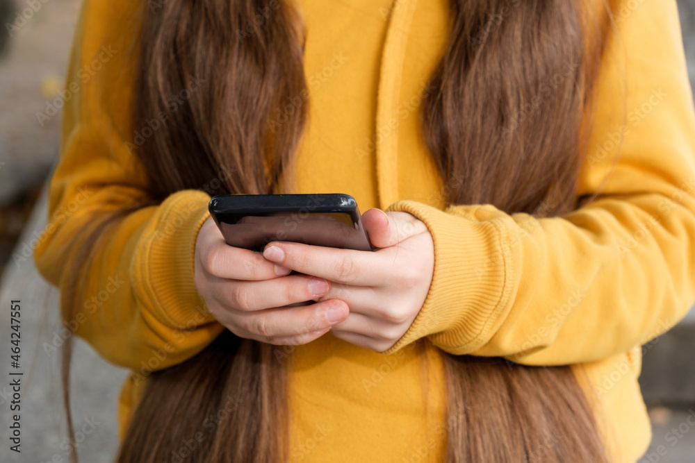 A girl with long hair holds a smartphone close-up. A girl with long hair holds a smartphone close-up.