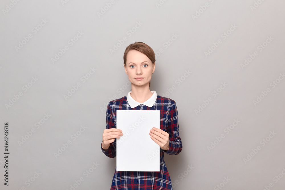 Studio portrait of serious young woman holding white blank paper sheet Studio portrait of serious young woman holding white blank paper sheet