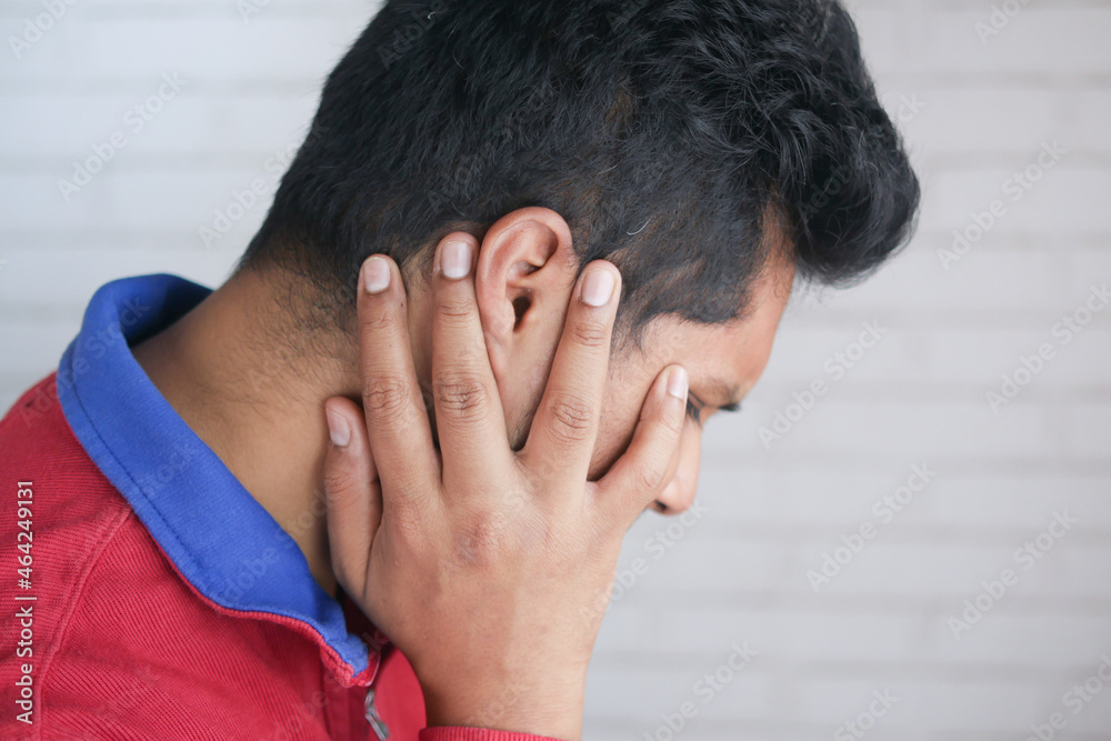 young man having ear pain touching his painful ear , young man having ear pain touching his painful ear ,