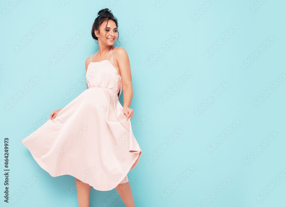 Portrait of young beautiful smiling female in trendy summer dress. Sexy carefree woman posing near blue wall in studio. Positive model having fun indoors. Cheerful and happy Portrait of young beautiful smiling female in trendy summer dress. Sexy carefree woman posing near blue wall in studio. Positive model having fun indoors. Cheerful and happy