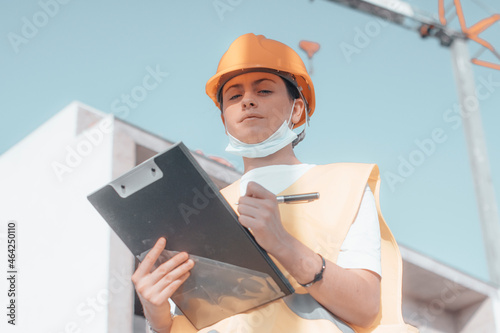Mujer joven arquitecta trabajando de ingeniera en la construcción de una estructura de casas con empleados de obra mientras estudia las ideas y planos