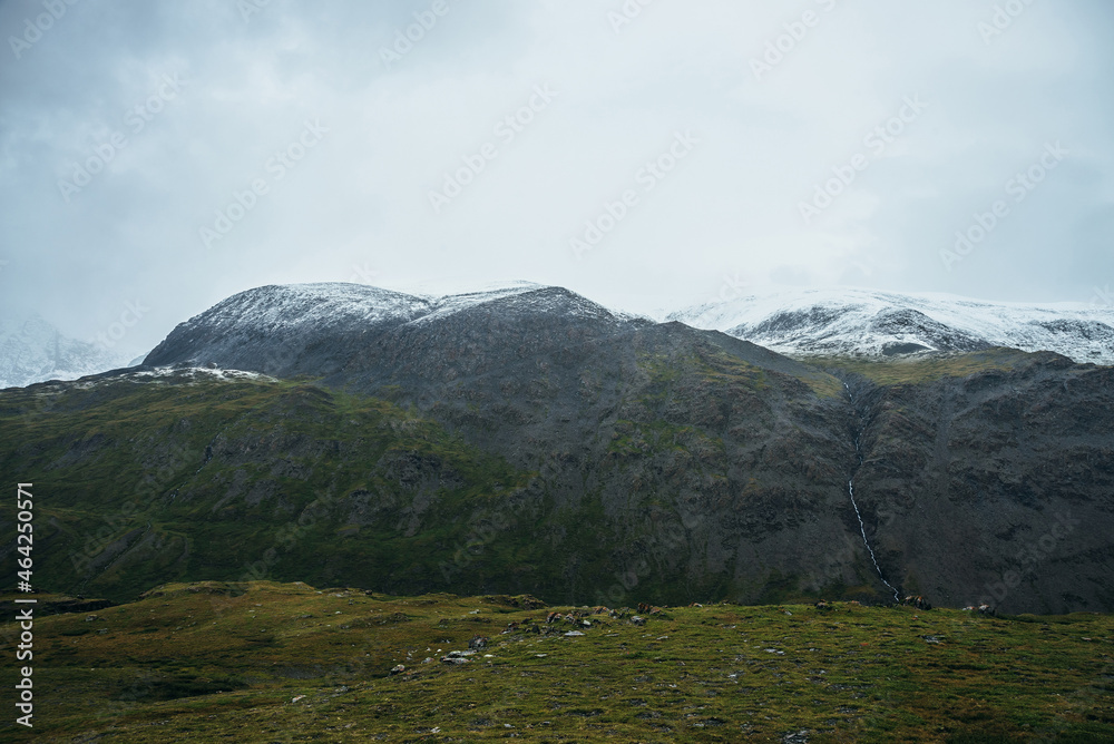 Minimalist alpine landscape with snowy mountains in low cloud in overcast weather. Deep gorge on background of snowbound mountain range under low cloudy sky. Atmospheric minimalism in high mountains. Minimalist alpine landscape with snowy mountains in low cloud in overcast weather. Deep gorge on background of snowbound mountain range under low cloudy sky. Atmospheric minimalism in high mountains.