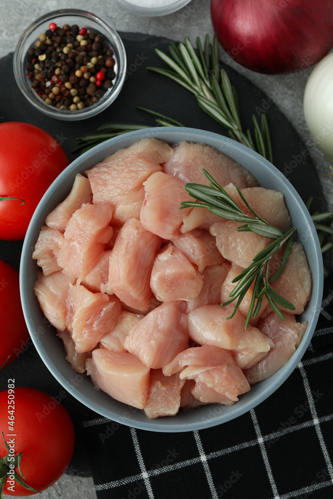 Concept of tasty food with slices of raw chicken fillet on gray texture background Concept of tasty food with slices of raw chicken fillet on gray texture background